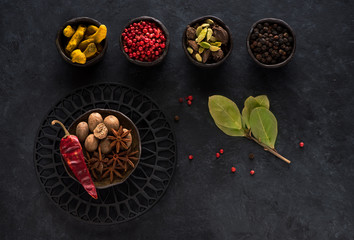 Indian spices and spicy in bowls on a black concrete background, top view, flat lay