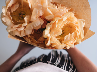 woman is holding wrapped flowers in her hand