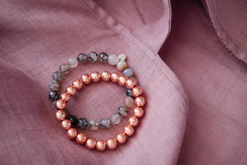 Rose gold gemstone bracelets on a soft blush linen fabric texture.  Female energy, fashion and beauty blogging concept