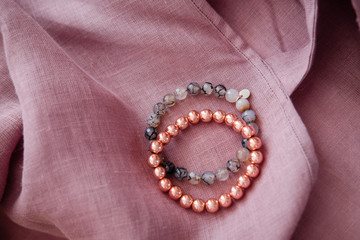 Rose gold gemstone bracelets on a soft blush linen fabric texture.  Female energy, fashion and beauty blogging concept