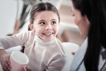 Fototapeta premium Watching you. Joyful girl expressing positivity, looking at her mother