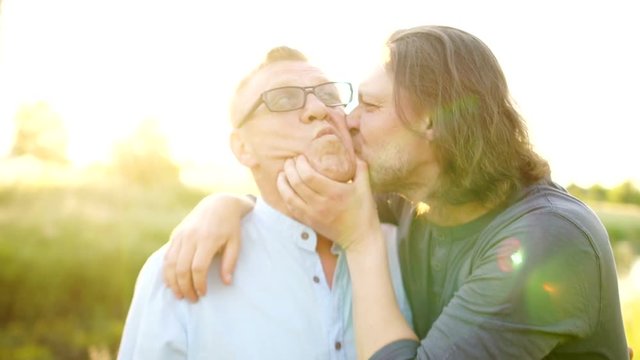 Father and adult son embrace. Close up portrait of a son kisses his father and he strokes his head. Father's Day