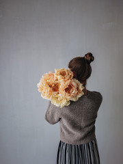 Woman holding peonies over her shoulder