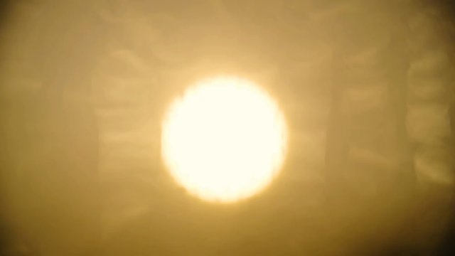 Refocus from sun to rain drops on window close-up 4K. Extreme long shot of sun in focus and refocus to window with raindrops. Bright yellow light.