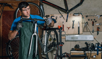 Fototapeta na wymiar Competent bicycle mechanic in a workshop repairs a bike.