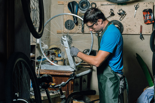 Competent bicycle mechanic in a workshop repairs a bike. - Powered by Adobe
