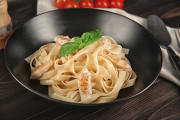Plate of tasty pasta with chicken fillet on table