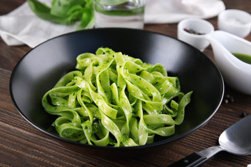 Plate of delicious pasta with pesto sauce on table