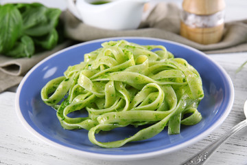 Plate of delicious pasta with pesto sauce on table