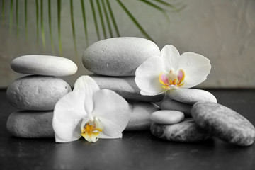 Fototapeta na wymiar Spa stones and beautiful orchid flowers on grey table