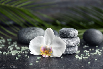 Spa stones and beautiful orchid flower on grey table