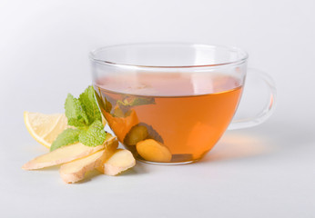 Cup of delicious tea with mint, ginger and lemon on grey background