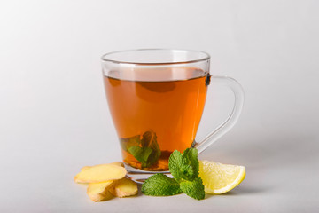 Cup of delicious tea with mint, ginger and lemon on grey background