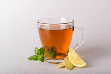 Cup of delicious tea with mint, ginger and lemon on grey background