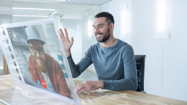 In the Near Future Man Makes Video Call from Computer with Transparent Display to His Friend. They Have Friendly Chat. Office Design is Modern and Bright.