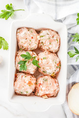 Raw homemade chicken or turkey meatballs in baking dish on white marble background. Copy space. top close view