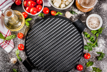 Homemade pasta pizza italian food ingredient on dark rusty table with flour, olive oil, basil, tomatoes and kitchen accessories top view