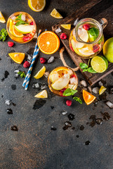 Summer cold cocktail, fruit and berry white sangria with apple, lemon, oranges and raspberry. dark background, copy space top view