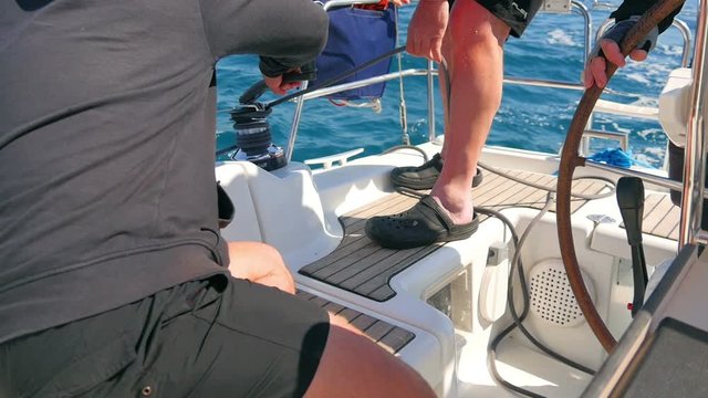 Male hands pulling blacke rope winded round side winch while making a turn. Filmed on sailing trip in Croatia in slow motion hd.