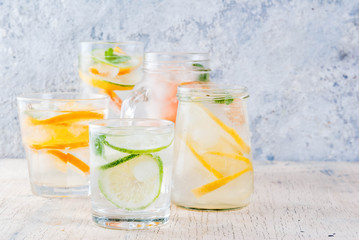 Summer healthy cocktails, set of various citrus infused waters, lemonades or mojitos, with lime lemon orange grapefruit, diet detox beverages, in different glasses light background copy space