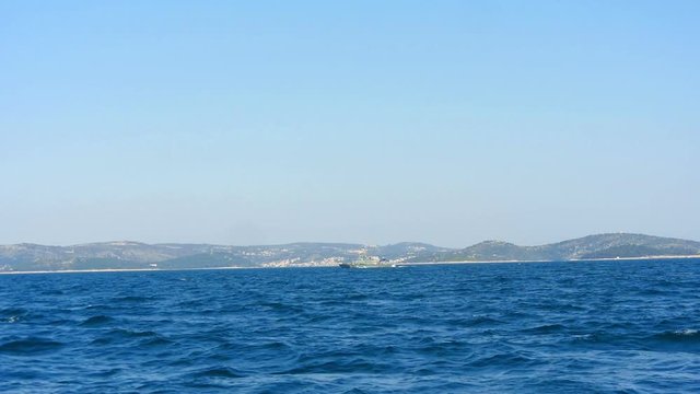 Military ship patrolling in Adriatic sea shot from distance from sailing boat. Filmed from moving sailing boat while sailing in Croatia.
