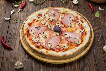 Delicious italian pizza with ham and mushrooms on wooden background