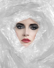 WOMAN WITH STRONG MAKE UP ROLLED UP IN PLASTIC
