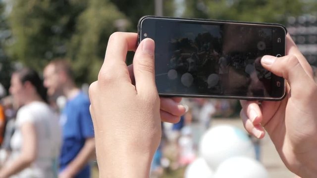 Person make Photos with Mobile Smart Phone in public Place with Crowd of People
