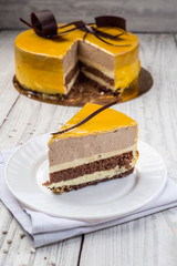 dark chocolate vegan cake with souffle cream and fruit mirror glaze on wooden background
