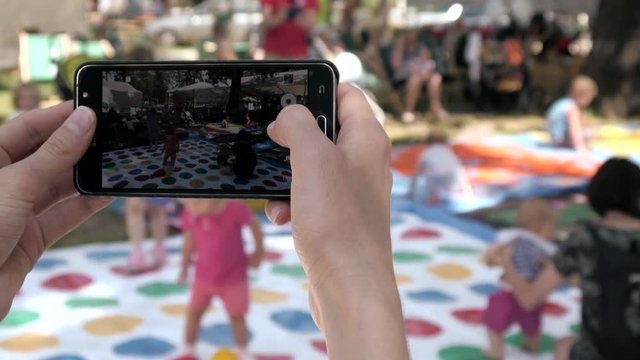 Person make Photos with Mobile Smart Phone in public Place with Crowd of People