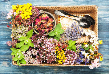Healing herbs and flowers for herbal tea and honeycomb in a tray  on a blue wooden background, top view, flat lay