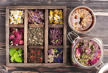 Medicinal herbs in a wooden box and a glass jar for herbal tea and tinctures. Herbal medicine, health, healing