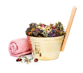 Accessories for baths and saunas. Brass bucket with herbs and flowers and bath towel on a white...