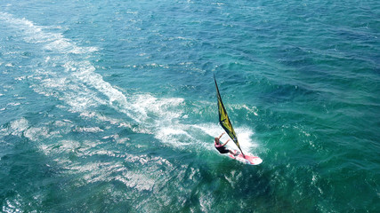 Aerial drone bird's eye view of surfer in tropical clear water beach