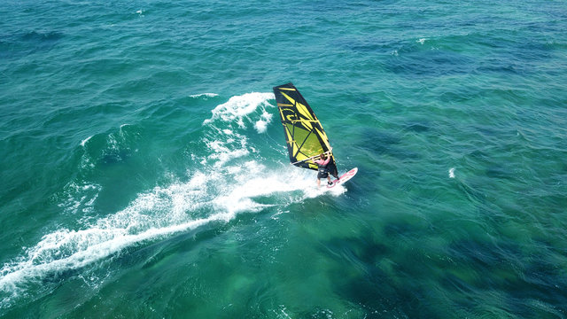 Aerial drone bird's eye view of surfer in tropical clear water beach