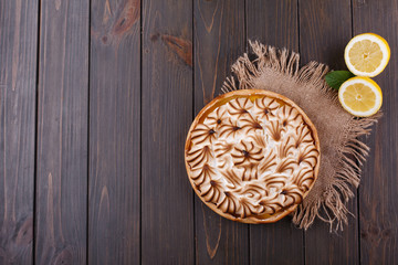 Tasteful lemon pie with white cream served on wooden table