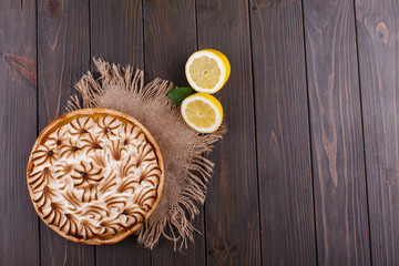 Tasteful lemon pie with white cream served on wooden table