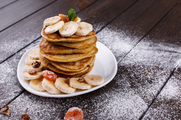 Tasty breakfast. Delicious puncakes with bananas, nuts and mint served on white plate
