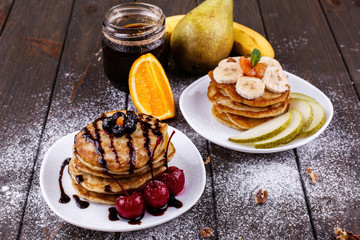Tasty breakfast. Delicious pancakes covered with chocolate, cherries, bananas and pears