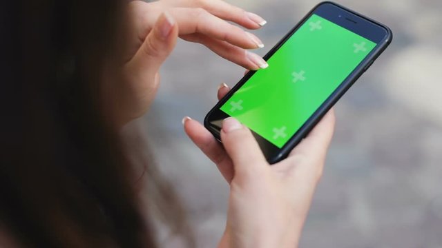 woman hands using cellular telephone smartphone with touch green screen for browsing social network communicating closeup view swapping tapping scrolling zooming chroma key display mock-up gadget