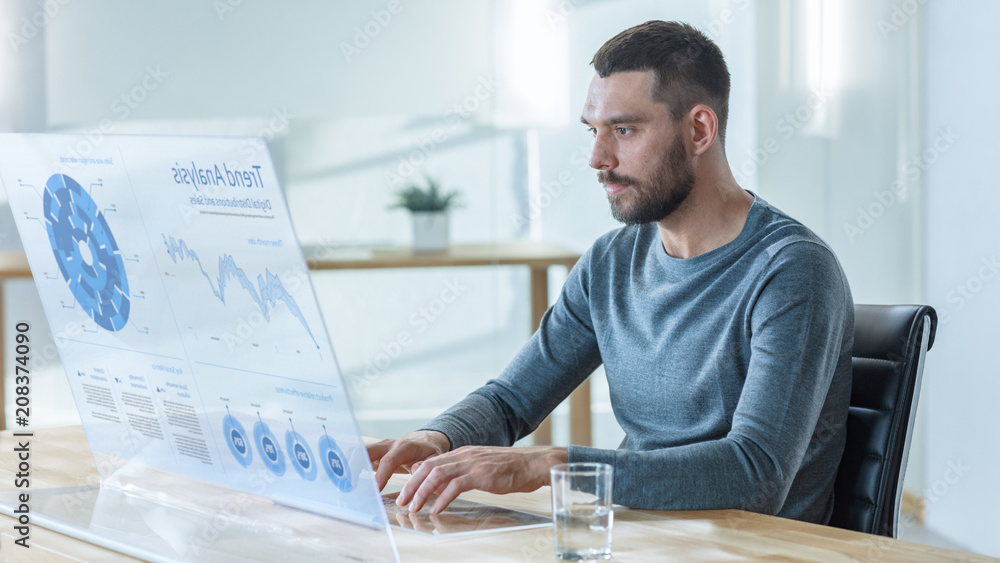 Poster in the near future man sitting at his workstation, works on his modern computer with transparent dis