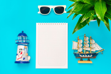 Flat lay traveler accessories -lighthouse, ship,  shell, glasses on the blue background with blank space for text. Top view travel or vacation concept. Summer background.Mock up.Copy space