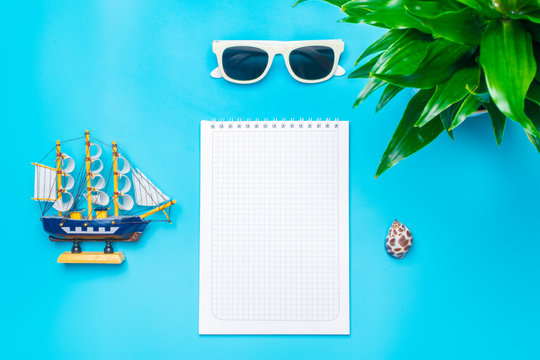 Flat lay traveler accessories -lighthouse, ship,  shell, glasses on the blue background with blank space for text. Top view travel or vacation concept. Summer background.Mock up.Copy space