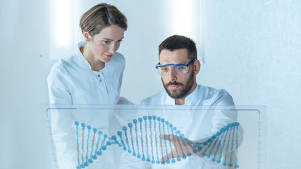 In the Futuristic Laboratory Male and Female Scientists Talk While Working on the Transparent Display Computer. Screen Shows Interactive DNA Visualisation and Futuristic User Interface.