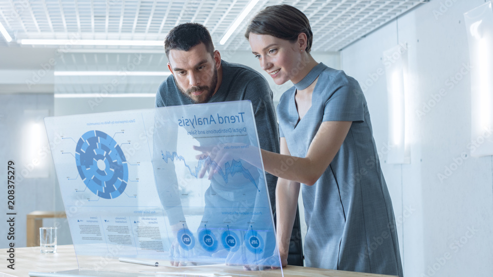 Poster in the near future male and female trade agents talk while working on the transparent display comput