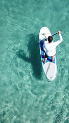 Aerial photo of man sup paddling with his cute dog in caribbean tropical beach with turquoise waters