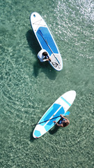 Aerial drone bird's eye view of a man exercising sup board in turquoise tropical clear waters at...