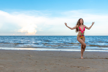 oung healthy woman with blonde curly hair doing yoga on the beach, heathy and relaxing concept.