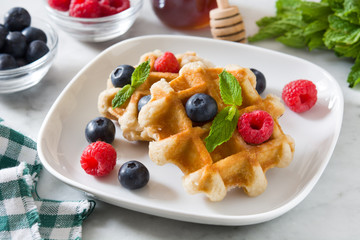 Traditional belgian waffles with blueberries and raspberries on white marble