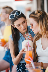 beautiful young girlfriends drinking summer cocktail together at beach bar